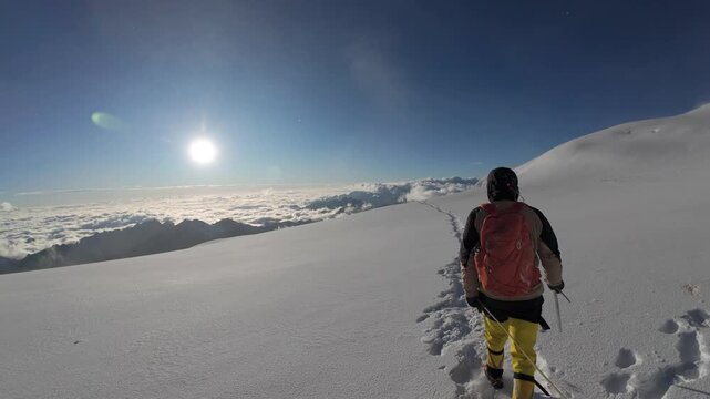Following Mountaineer Hiking Across Snow Covered Glacier Above The Clouds On Huayna Potosi In Bolivia