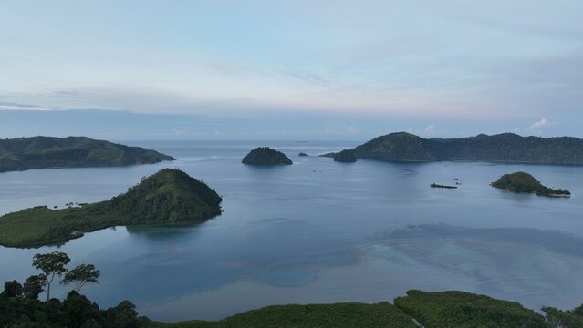 Aerial view of the Mandeh islands surrounded by lush tropical greenery and calm blue waters in Koto XI Tarusan, West Sumatra, Indonesia.