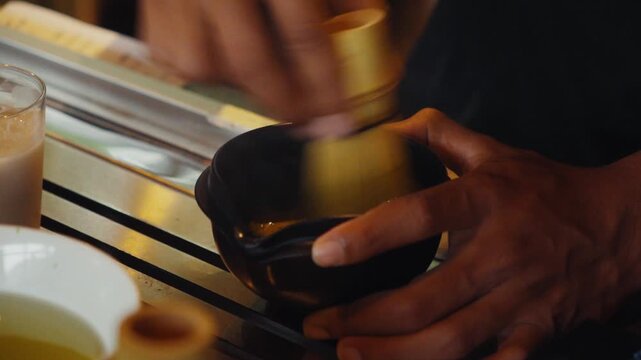 Barista whisking matcha green tea powder in bowl