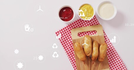 On start, infographic icons drifting, clustering over corn dogs and sauces, showing eco metrics © vectorfusionart