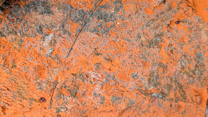 Rough textured surface presenting an abstract pattern of cracked orange paint with gray and white concrete debris, creating a distressed industrial background overlay © Newleks
