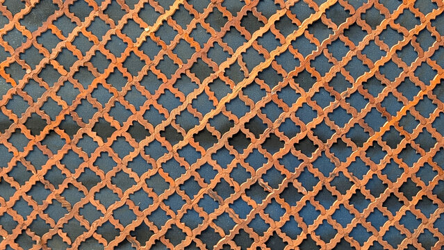 Ornate arabic geometric screen creating an intricate, repeating pattern of elegant wooden trellis and lattice design with decorative motifs over a dark background