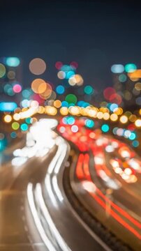 Blurry nighttime cityscape with traffic lights and road curves sharply