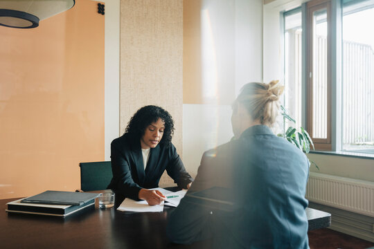 Mature female executive discussing contract details with female colleague in office