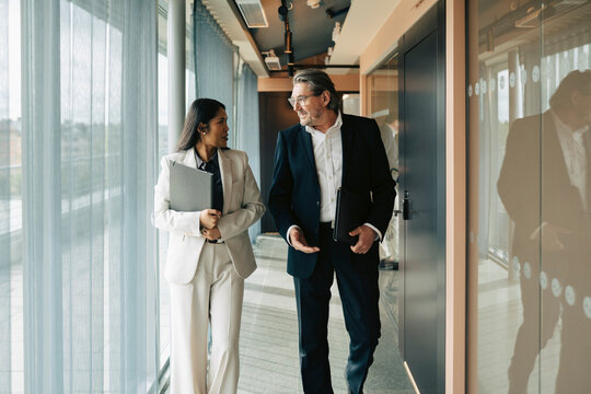 Senior businessman and female employee having conversation on their way to meeting