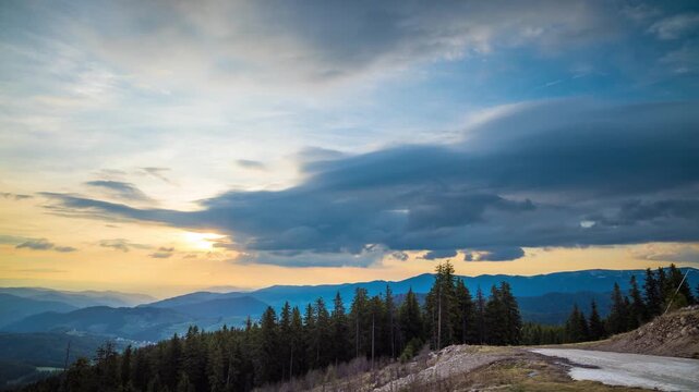 Valley with peaks of the Rhodope Mountains covered with spruce forests is shaded under a cloudy evening sky