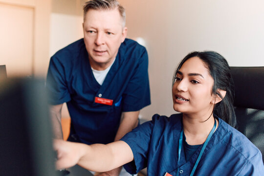 Female health professional discussing data with her male coworker while pointing at computer screen