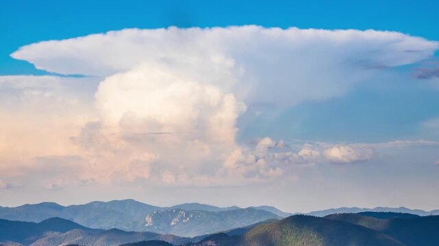 Dangerous clouds scatter across the sky from a explosion in the depths of the Rhodope Mountains with spruce forests, meadows and villages