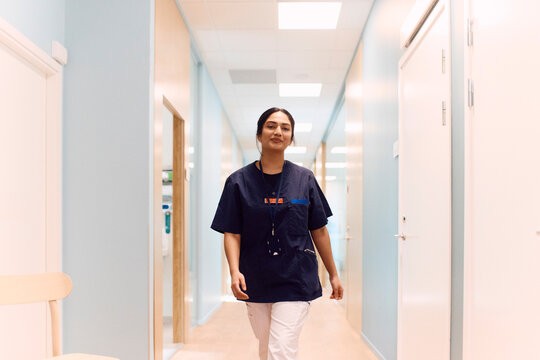Portrait of female medical practitioner walking confidently in hospital corridor