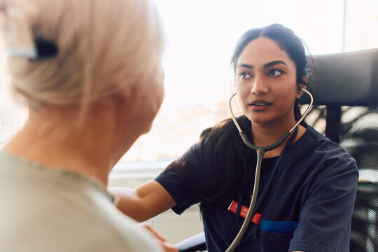 Female doctor listening to patient's heartbeat with stethoscope during checkup
