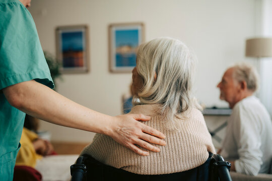 Female nurse supporting elderly woman at retirement home