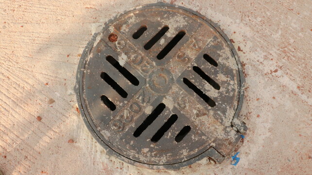 Old rusty metal drain cover on concrete floor with concrete infrastructure circular drainage industrial