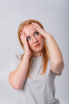 Young woman experiencing intense headache, holding her head with hands while looking up, representing concepts of stress, worry, and emotional exhaustion