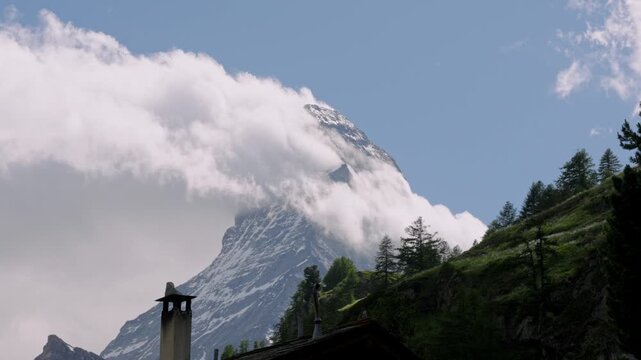 Dramatic clouds swirling around the iconic matterhorn peak in the swiss alps on a bright sunny day