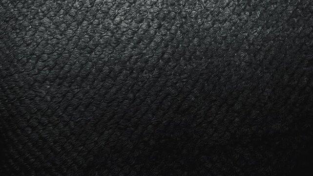 macro textured black fabric background with intricate knitted yarn loops illuminated by soft cinematic side lighting