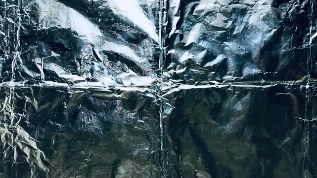 textured tinfoil background with abstract metallic crinkles gleaming under stark cinematic lighting