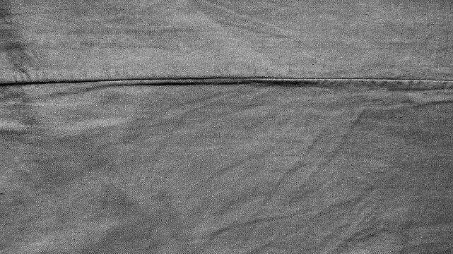 textured dark grey denim fabric showing detailed weave pattern and central stitched seam in a macro close up
