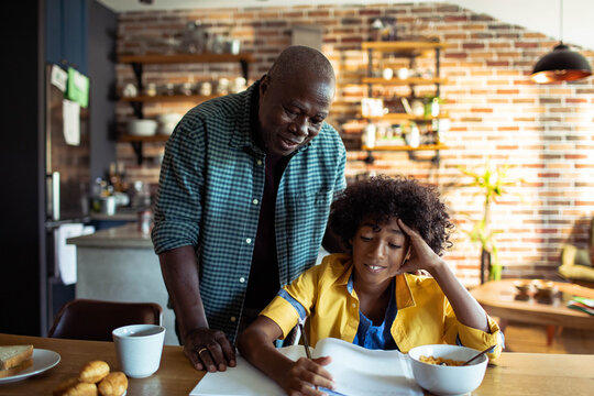 Parent helping child with homework at kitchen table