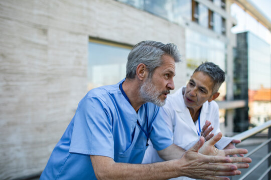 Senior healthcare professionals discussing patient care outside hospital