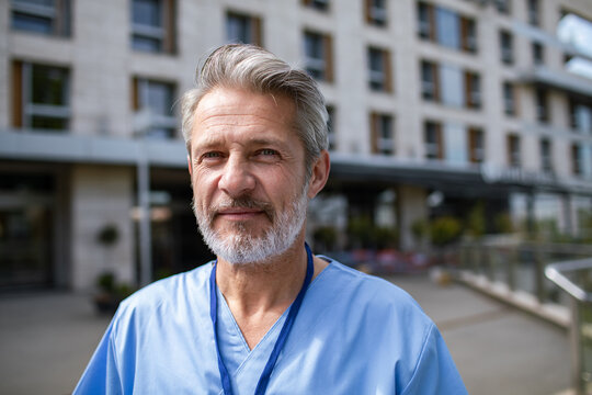 Senior male healthcare worker smiling outside hospital