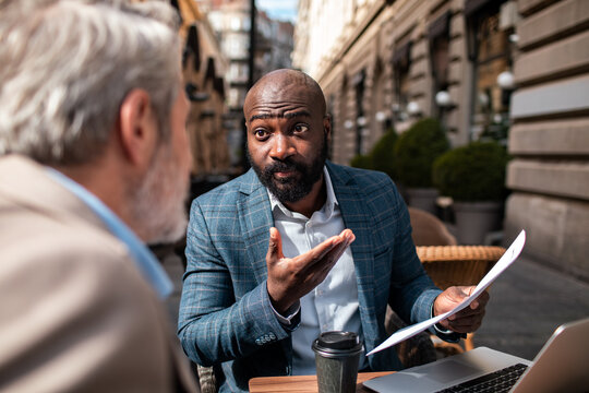Two businessmen discussing documents at outdoor cafe