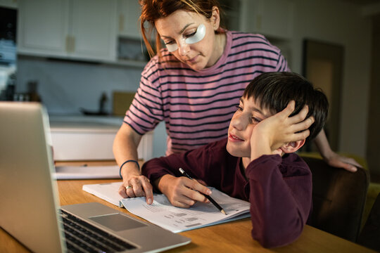 Parent helping child with online homework at kitchen table