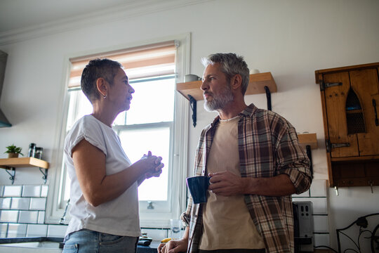 Mature couple talking over coffee in home kitchen