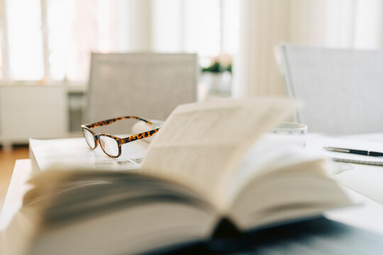 Eyeglasses resting on open book on desk in retirement
