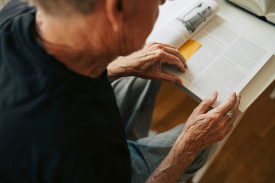 Over the shoulder view of elderly man reading book in retirement home