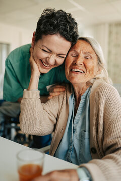 Happy female nurse showing affection to senior woman at retirement home