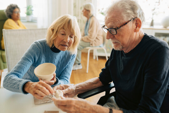 Senior man and woman working on pottery art project together at retirement home