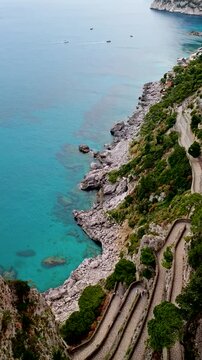 Aerial 4K drone vertical video footage of Via Krupp winding stairs with breathtaking landscape on Capri Island, Italy, dramatic cliffs, turquoise sea and iconic Mediterranean coastal scenery