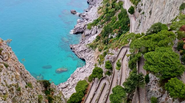 Aerial 4K drone video footage of Via Krupp winding stairs with breathtaking landscape on Capri Island, Italy, dramatic cliffs, turquoise sea and iconic Mediterranean coastal scenery