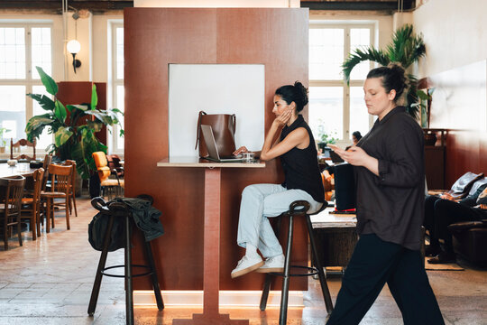 Diverse freelancers working and moving around inside busy open-plan coworking lounge