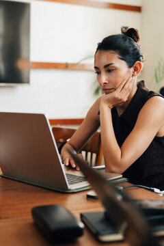 Focused female entrepreneur leaning on elbow while working on her laptop at shared workspace
