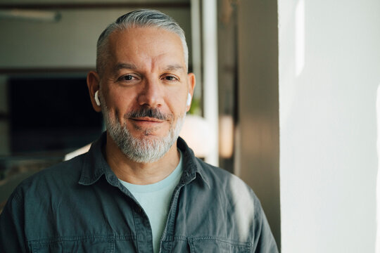 Portrait of smiling male entrepreneur wearing wireless in-ear headphones