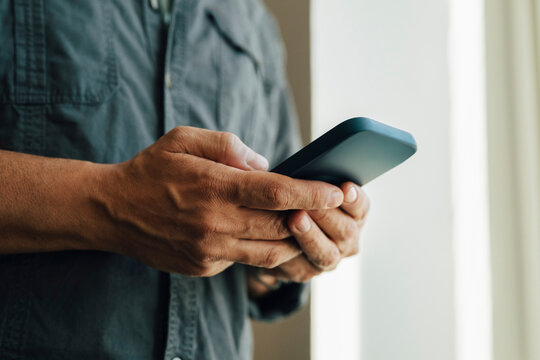 Midsection of male entrepreneur text messaging through smart phone at office