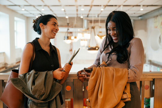 Happy diverse businesswomen laughing during friendly conversation at coworking space