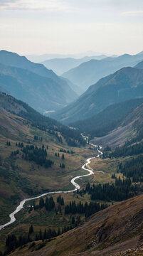 Winding river carving through green mountain valley seen from above