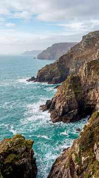 Dramatic coastal cliffs plunging into turquoise sea under bright sky
