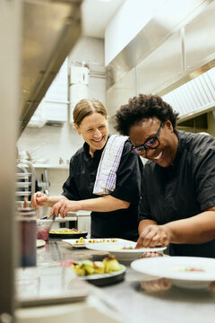 Happy female chefs talking with each other while working in commercial kitchen