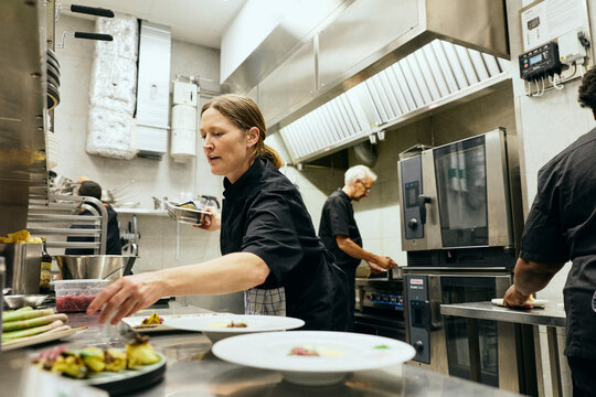 Kitchen team coordinating and passing tools while working at restaurant service counter