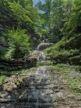Tall Forest Waterfall Cascading Down Layered Rock Cliff