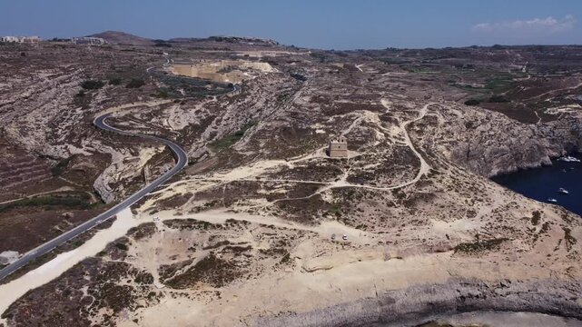 Aerial view of Dwerja bay in Gozo at noon with clear skies and rock formations brown and gray earth tones and natural beauty for nature documentarie. High quality 4k footage