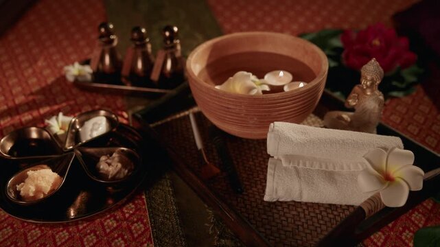 Top view Thai relax Oil spa treatment items arranged on woven mat in interior wellness room, warm light.