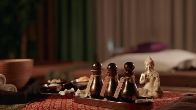 Spa oil bottles and small buddha statue on treatment table in Thai massage room dolly.