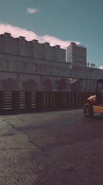 A construction vehicle works on a site next to a large, multi story building. The scene shows a mix of machinery and architecture during daylight hours.