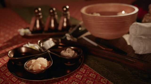 Thai relax Oil spa bowl scrub and oil bottles arranged on treatment table with towels.