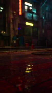 Water collects on the ground in a city street at night. Colorful lights reflect off the wet surface. Buildings and neon signs are visible in the background.