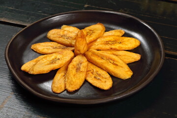 Sliced ​​and fried plantain served on a ceramic plate. © Luiz Henrique Mendes